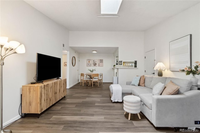 living area with baseboards, wood finished floors, and a skylight