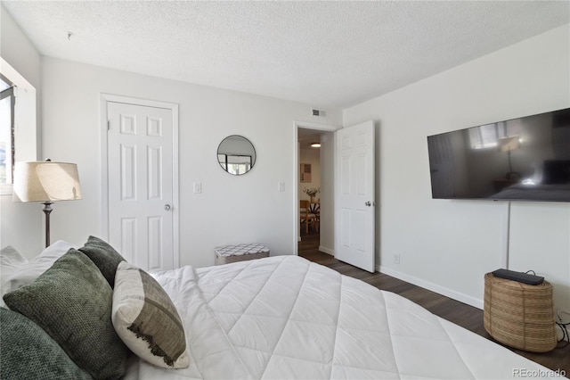 bedroom with visible vents, a textured ceiling, baseboards, and dark wood-style floors