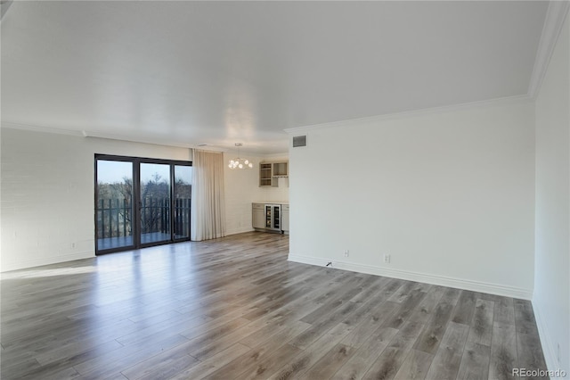 unfurnished living room featuring hardwood / wood-style floors, crown molding, and a notable chandelier