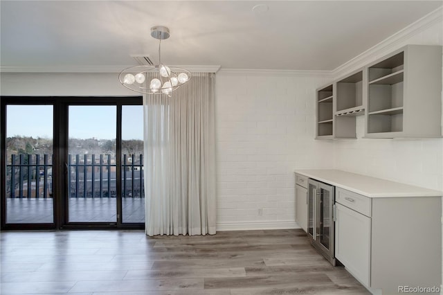 kitchen featuring wine cooler, crown molding, a chandelier, decorative light fixtures, and light wood-type flooring