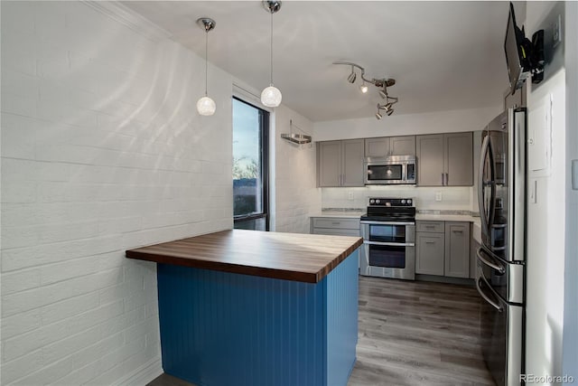 kitchen featuring kitchen peninsula, appliances with stainless steel finishes, dark wood-type flooring, pendant lighting, and butcher block countertops