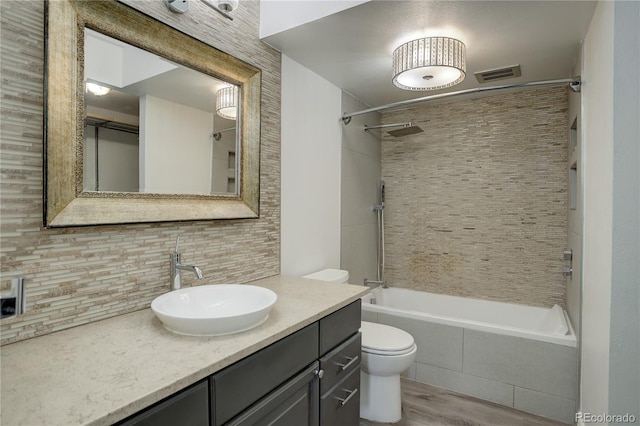 full bathroom with tasteful backsplash, vanity, hardwood / wood-style floors, toilet, and tiled shower / bath