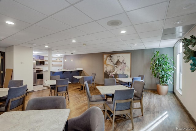 dining room featuring a paneled ceiling, light hardwood / wood-style floors, and sink