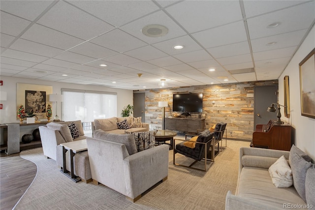 living room with light hardwood / wood-style floors, a drop ceiling, and wood walls