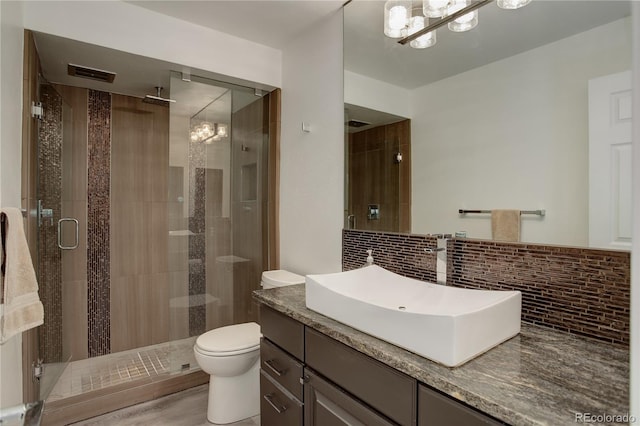 bathroom featuring backsplash, hardwood / wood-style flooring, toilet, an enclosed shower, and a chandelier