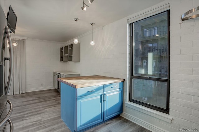 kitchen with blue cabinets, light wood finished floors, hanging light fixtures, butcher block countertops, and stainless steel fridge