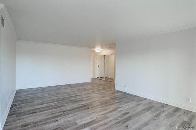 empty room with light wood-style floors, baseboards, and crown molding