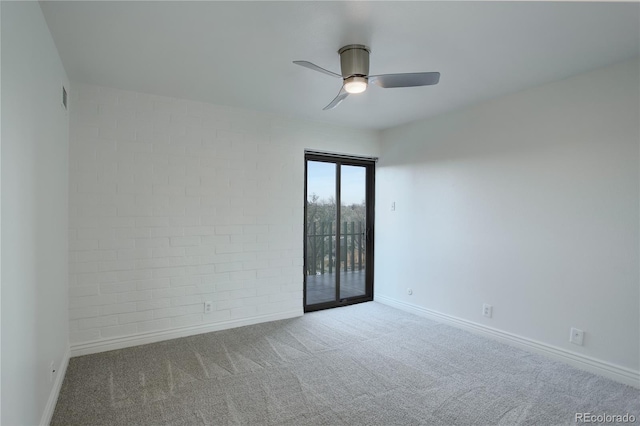 carpeted spare room with a ceiling fan, brick wall, and baseboards