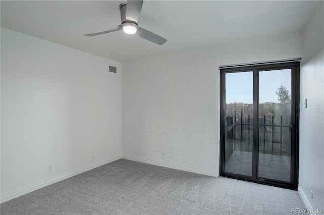 carpeted empty room featuring ceiling fan, brick wall, visible vents, and baseboards