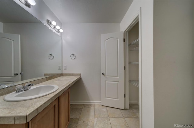 19249 E 58th Ave Unit D, Denver, CO 80249 - bathroom with vanity, baseboards, tile patterned flooring, and a walk in closet