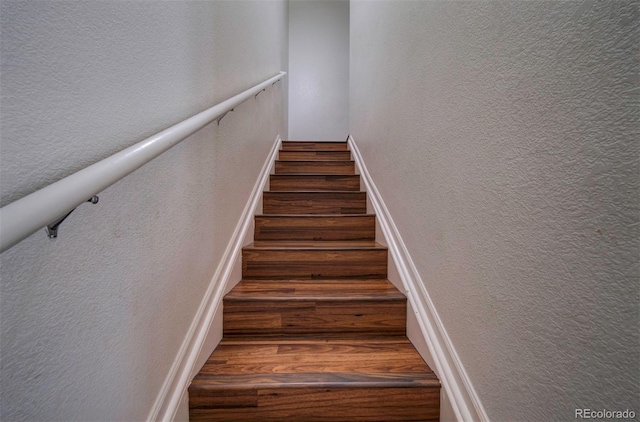 19249 E 58th Ave Unit D, Denver, CO 80249 - stairway featuring wood finished floors, a textured wall, and baseboards