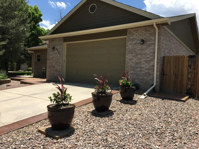 5461 S Youngfield Ct, Littleton, CO 80127 - view of front of house with brick siding, driveway, and a garage