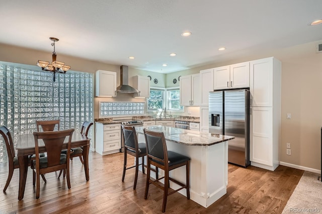 5461 S Youngfield Ct, Littleton, CO 80127 - kitchen with stainless steel appliances, wall chimney range hood, a chandelier, light stone countertops, and white cabinetry