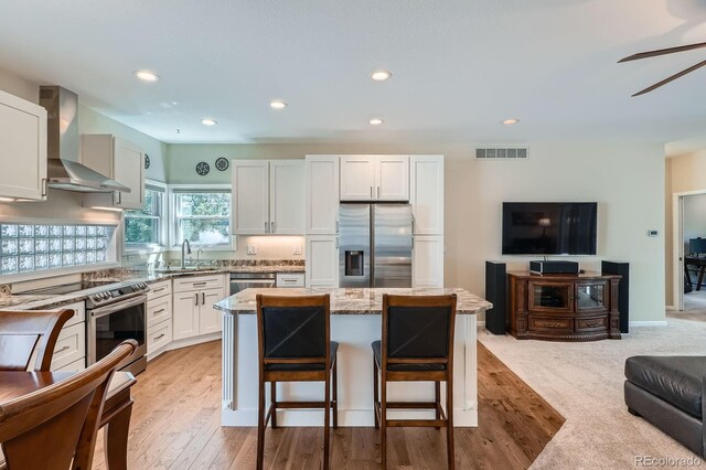 5461 S Youngfield Ct, Littleton, CO 80127 - kitchen with stainless steel appliances, wall chimney exhaust hood, open floor plan, light stone counters, and a sink