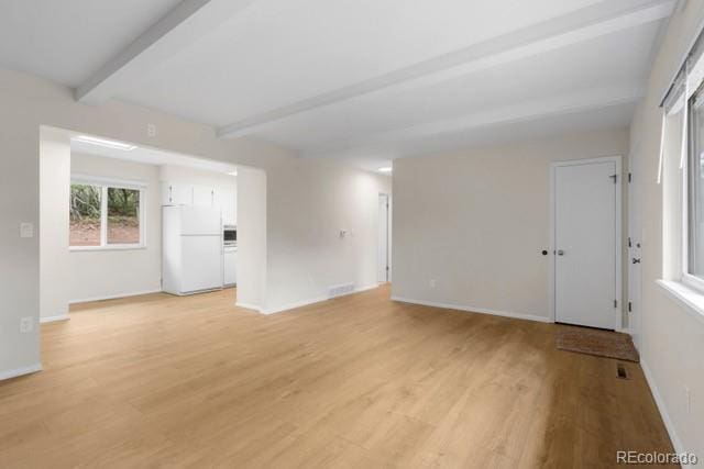 unfurnished room with beamed ceiling and light hardwood / wood-style floors