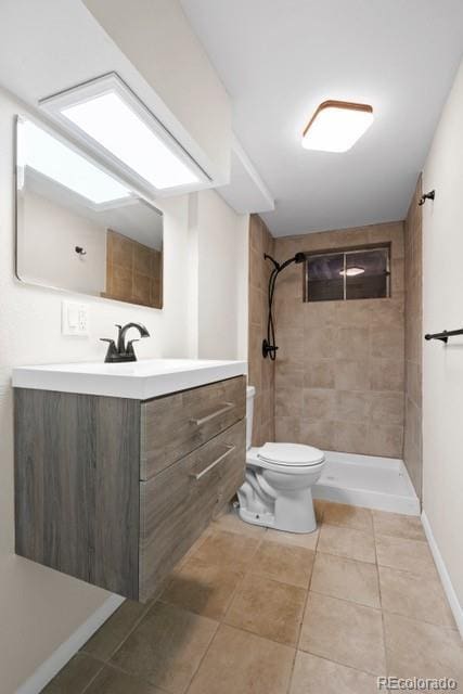 bathroom with tiled shower, vanity, toilet, and tile patterned flooring