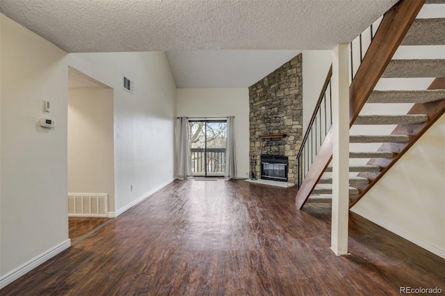 unfurnished living room featuring visible vents, vaulted ceiling, stairway, and wood finished floors