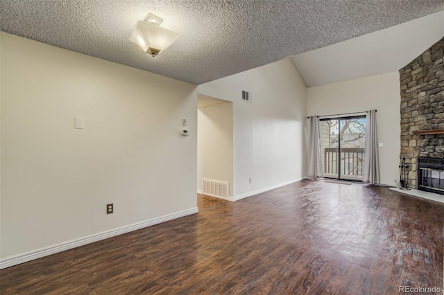 unfurnished living room with lofted ceiling, a fireplace, visible vents, and wood finished floors