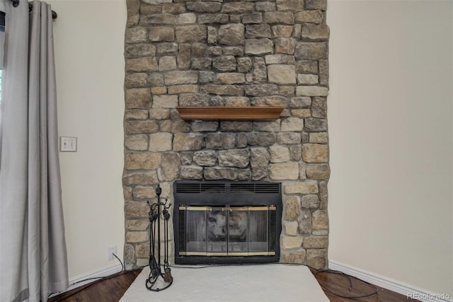 details with baseboards, a fireplace, heating unit, and wood finished floors