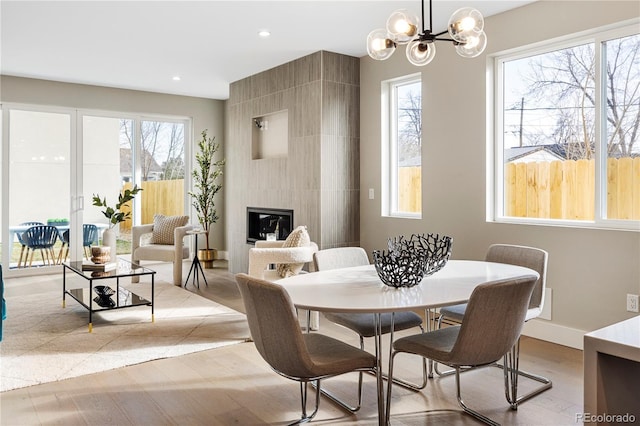 dining room with an inviting chandelier, a large fireplace, and a wealth of natural light