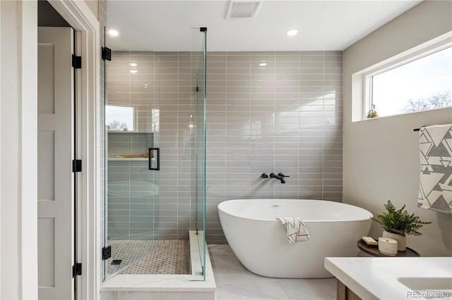 bathroom featuring shower with separate bathtub, tile walls, tile patterned floors, and vanity