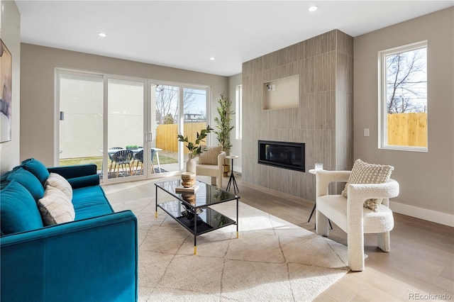 living room with a wealth of natural light, light hardwood / wood-style flooring, and a large fireplace