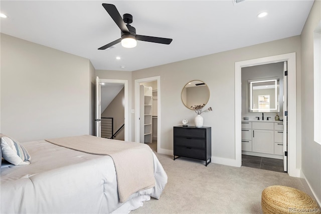 bedroom with connected bathroom, a spacious closet, light carpet, a closet, and ceiling fan