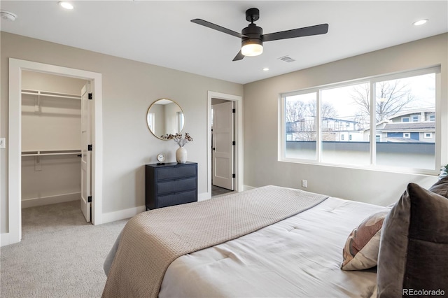 carpeted bedroom with a walk in closet, a closet, and ceiling fan