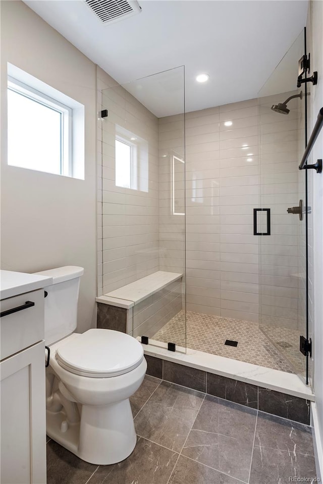 bathroom featuring vanity, a shower with door, and toilet