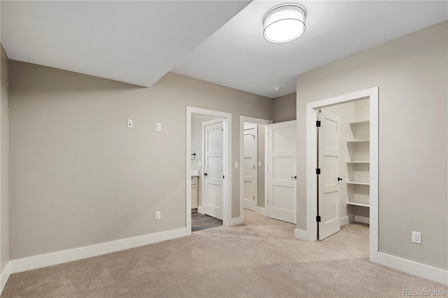 unfurnished bedroom with a walk in closet, light colored carpet, and a closet