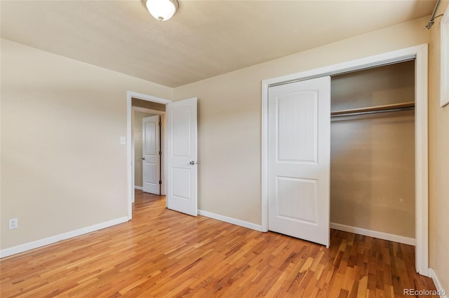 unfurnished bedroom featuring light wood finished floors, a closet, and baseboards