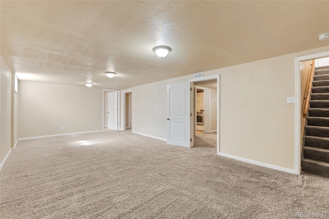 finished below grade area featuring stairway, visible vents, baseboards, a textured ceiling, and carpet flooring