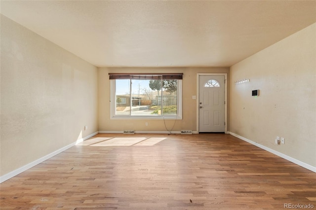 foyer entrance with visible vents, baseboards, and light wood-style floors