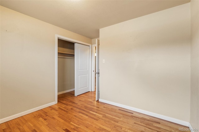 unfurnished bedroom with light wood-style flooring, baseboards, and a closet