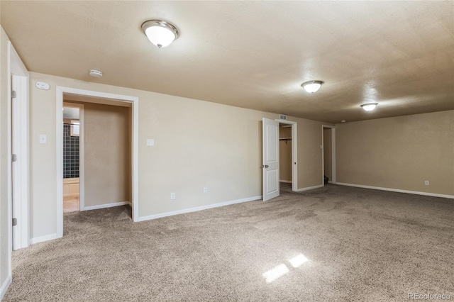 empty room featuring baseboards, a textured ceiling, and carpet