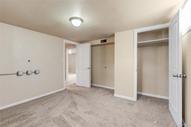 unfurnished bedroom with visible vents, multiple closets, a textured ceiling, carpet floors, and baseboards