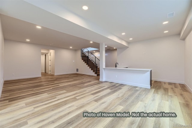 basement featuring light hardwood / wood-style flooring and sink