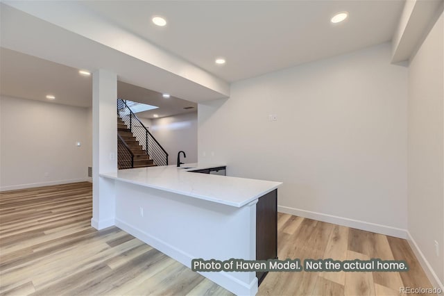 kitchen featuring kitchen peninsula, sink, and light hardwood / wood-style flooring