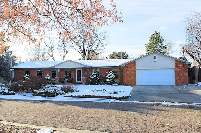 single story home featuring driveway, brick siding, and an attached garage