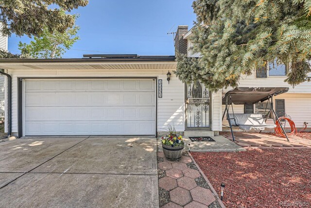 15531 E Jewell Pl, Aurora, CO 80013 - view of front facade with concrete driveway, an attached garage, and a chimney
