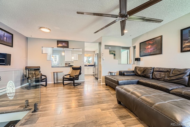15531 E Jewell Pl, Aurora, CO 80013 - living area featuring a textured ceiling, light wood-type flooring, ceiling fan, and baseboards