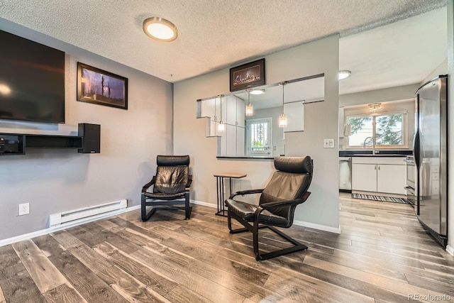 15531 E Jewell Pl, Aurora, CO 80013 - sitting room featuring a baseboard heating unit, hardwood / wood-style flooring, healthy amount of natural light, baseboards, and a textured ceiling
