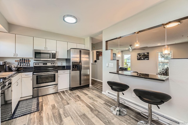 15531 E Jewell Pl, Aurora, CO 80013 - kitchen featuring appliances with stainless steel finishes, dark countertops, light wood finished floors, baseboard heating, and white cabinetry