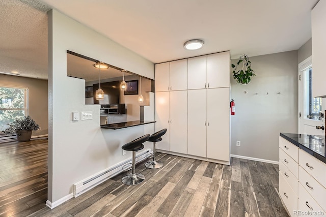 15531 E Jewell Pl, Aurora, CO 80013 - kitchen featuring dark wood finished floors, a baseboard radiator, white cabinets, dark countertops, and baseboards