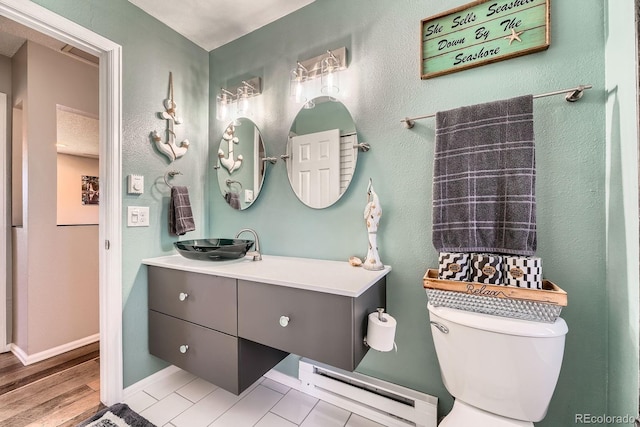 15531 E Jewell Pl, Aurora, CO 80013 - bathroom with baseboard heating, vanity, toilet, baseboards, and wood finished floors