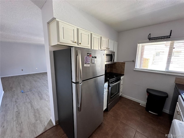 8047 Wolff St Unit H, Westminster, CO 80031 - kitchen featuring appliances with stainless steel finishes, a textured ceiling, decorative backsplash, dark countertops, and baseboards