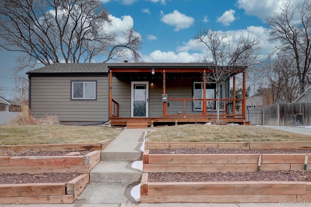 view of front of property featuring a front yard, covered porch, and fence