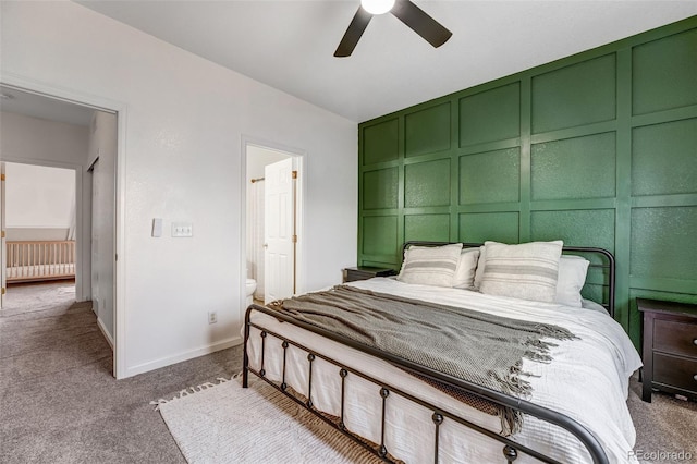 bedroom featuring a decorative wall, carpet, ensuite bathroom, a ceiling fan, and baseboards