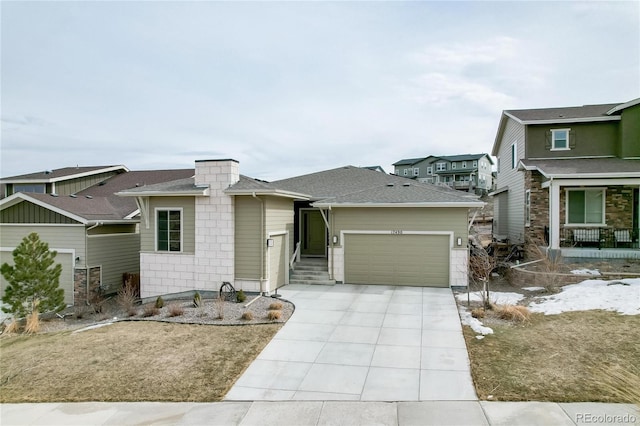 view of front of house featuring a garage, concrete driveway, and a shingled roof