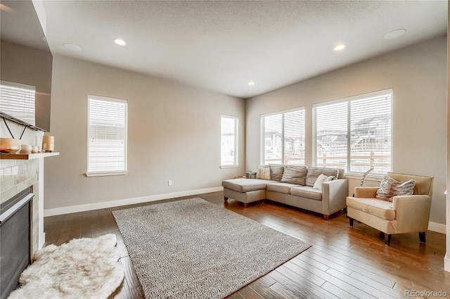 living area with recessed lighting, wood-type flooring, a fireplace, and baseboards